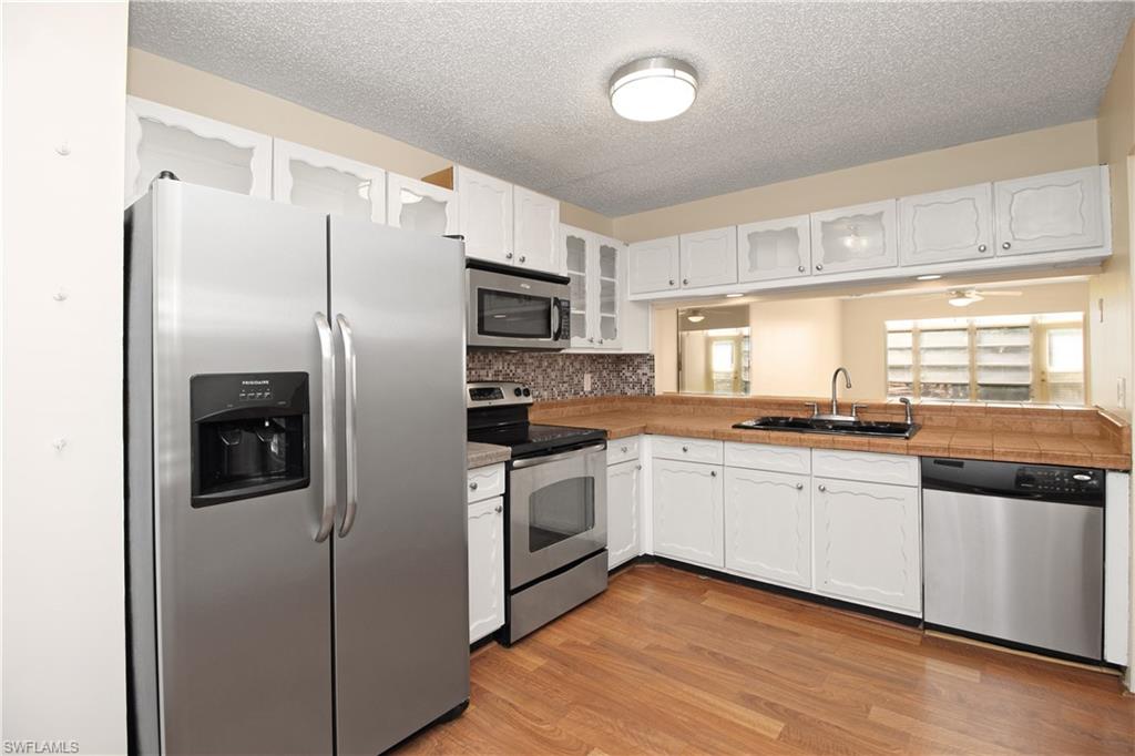 3471 County Barn Road, Unit F103 Naples, FL 34112 - Photo 8 of 27 a kitchen with stainless steel appliances a refrigerator sink and stove