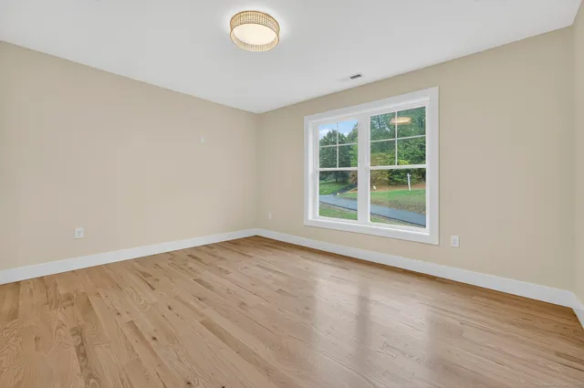 a spacious bedroom with a bed and wooden floor