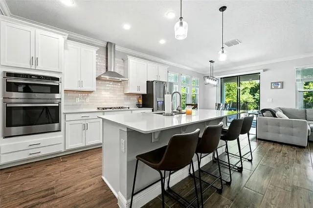 a kitchen with a stove a sink dishwasher a refrigerator and wooden cabinets with wooden floor