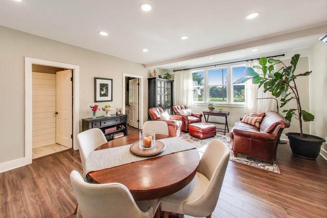 a living room with furniture a large window and wooden floor