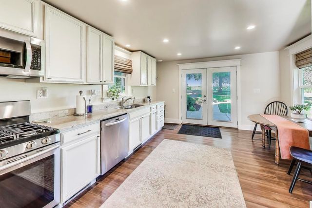 a kitchen with stainless steel appliances granite countertop a stove a sink and a microwave