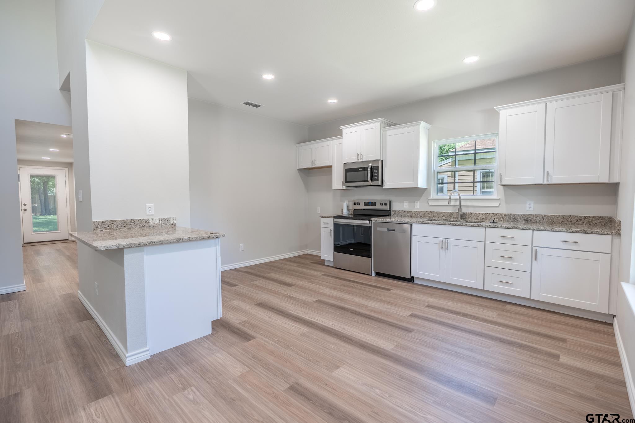 233 Harrison Street Longview, TX 75601 - Photo 11 of 44 a large kitchen with stainless steel appliances granite countertop a stove top oven a sink dishwasher and white cabinets with wooden floor