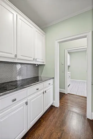 a view of an empty room with wooden floor and a ceiling fan