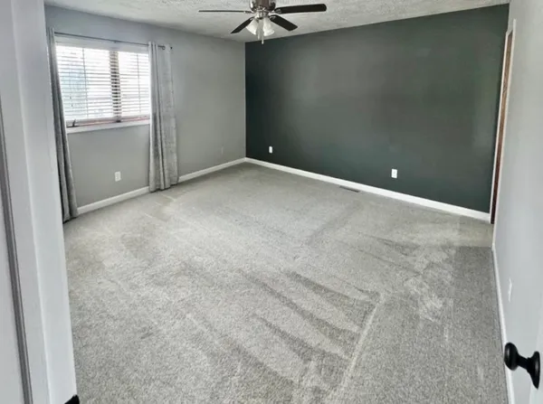 an empty room with windows and fan