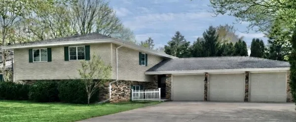 a front view of a house with a garden and trees