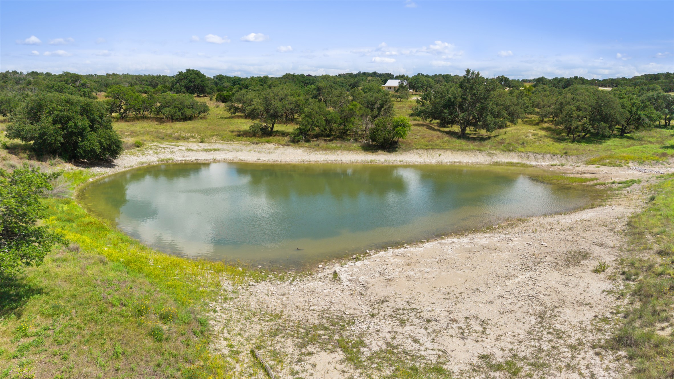 4112 Schumann Road Stonewall, TX 78671 - Photo 5 of 10 A tranquil pond awaits on this sprawling property, surrounded by natural greenery and open spaces.