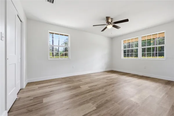 an empty room with wooden floor and a ceiling fan