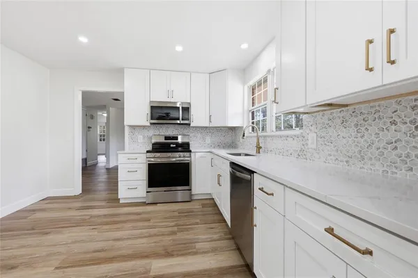 a kitchen with granite countertop white cabinets and stainless steel appliances