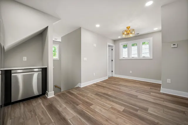 a view of an empty room with window and wooden floor