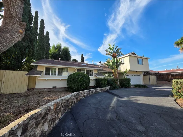 a front view of a house with a yard and potted plants