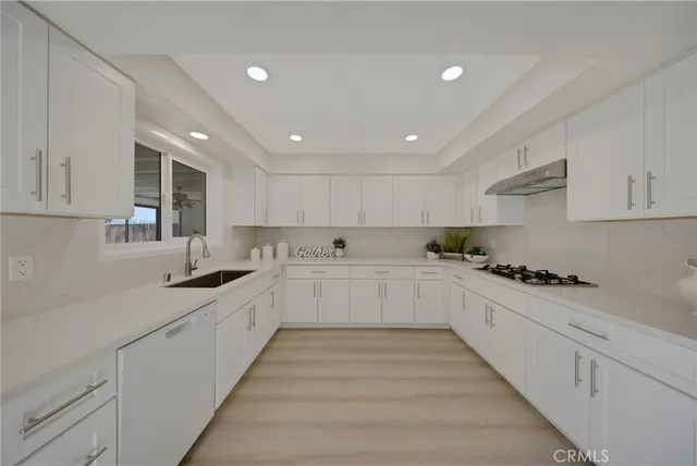 a large white kitchen with stainless steel appliances granite countertop lots of white cabinets a sink and dishwasher