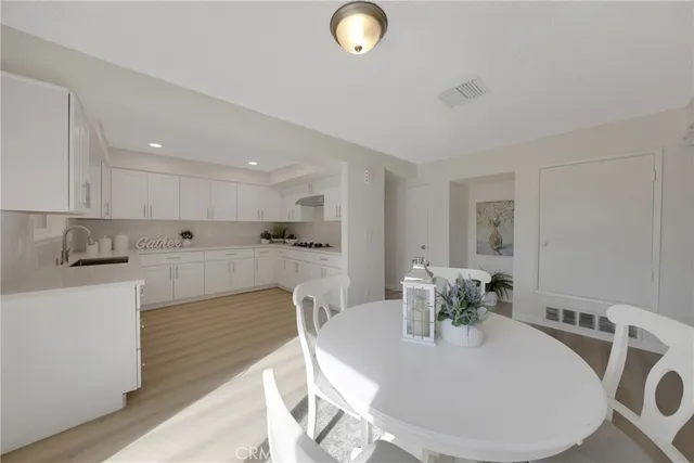 a large white kitchen with stainless steel appliances kitchen island granite countertop a dining table chairs and granite counter tops