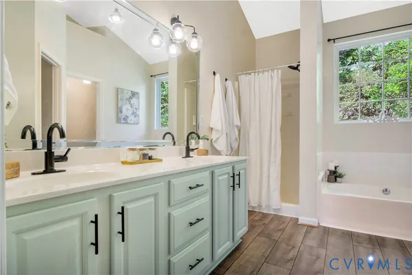a bathroom with a double vanity sink a mirror and a bathtub