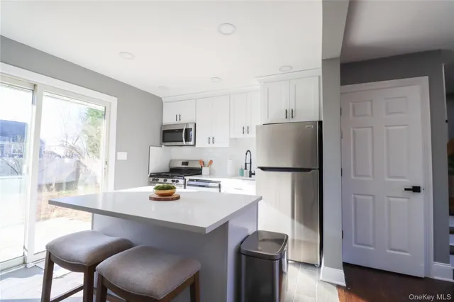 a kitchen with a refrigerator a stove a sink and white cabinets with wooden floor