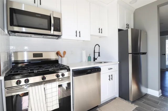 a kitchen with stainless steel appliances a refrigerator stove and white cabinets