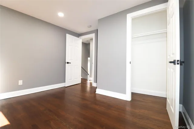 an empty room with wooden floor & closet area