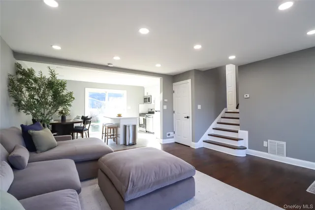 a living room with furniture and a dining table with wooden floor