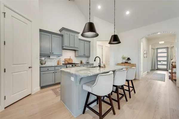 a kitchen with stainless steel appliances granite countertop a sink a stove and chairs