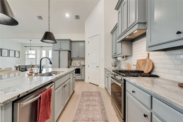 a kitchen with stainless steel appliances granite countertop a sink a stove and a wooden floors