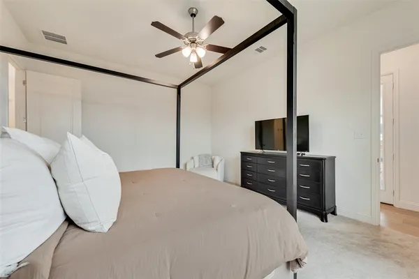 a bedroom with a large bed and a flat tv screen on dresser
