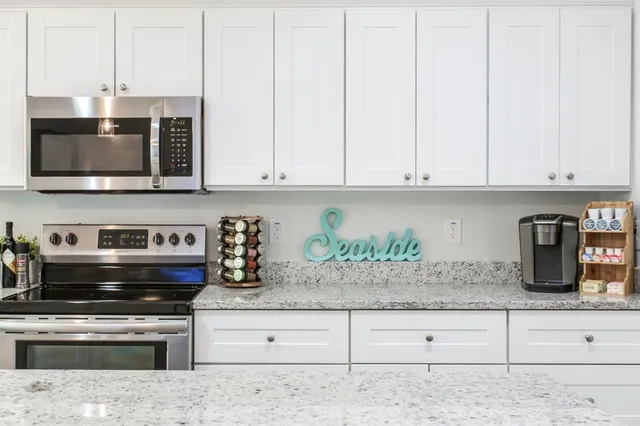 a kitchen with granite countertop white cabinets and stainless steel appliances