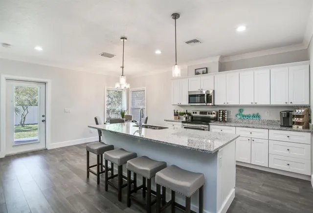 a kitchen with stainless steel appliances granite countertop a stove a sink a microwave a center island and furniture