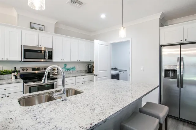 a kitchen with kitchen island granite countertop a sink counter top space appliances and cabinets