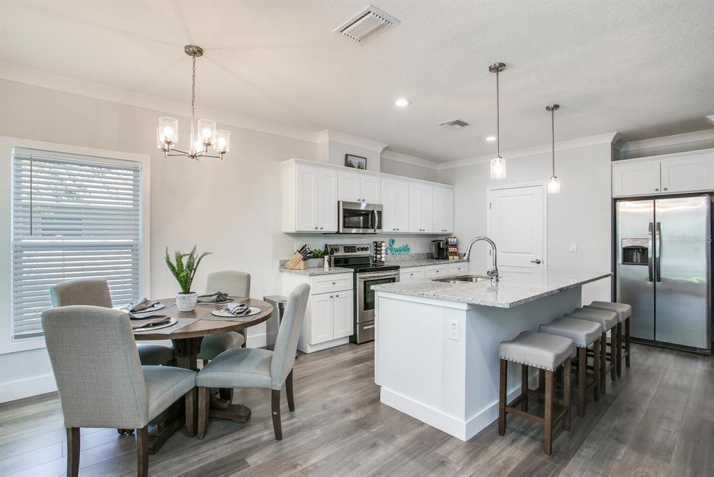 3040 Belcher Road Dunedin, FL 34698 - Photo 7 of 24 a kitchen with kitchen island a dining table and chairs