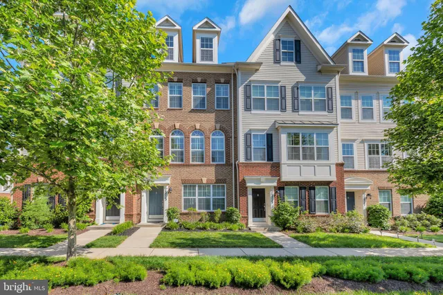 a large kitchen with stainless steel appliances a large counter top a refrigerator a stove a sink and a wooden floor