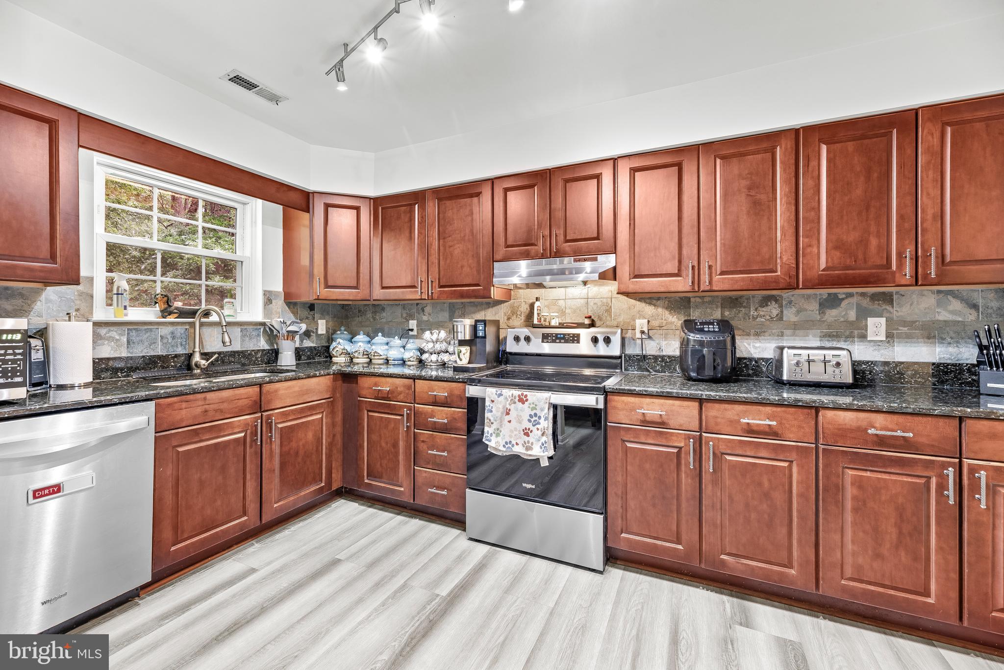 8328 Ridge View Road Lusby, MD 20657 - Photo 8 of 34 a kitchen with stainless steel appliances granite countertop wooden cabinets a sink and dishwasher with wooden floor