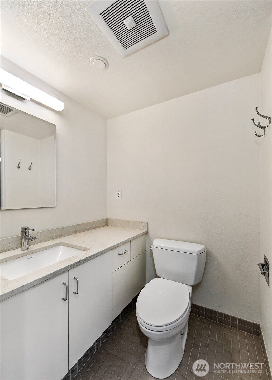 1101 Seneca Street, Unit 1301 Seattle, WA 98101 - Photo 21 of 40 a bathroom with a granite countertop toilet a sink and a mirror