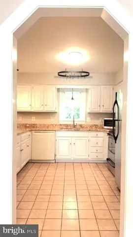 a large kitchen with kitchen island a stove a sink dishwasher and white cabinets with wooden floor