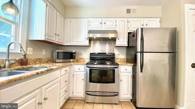 a kitchen with appliances a sink and cabinets