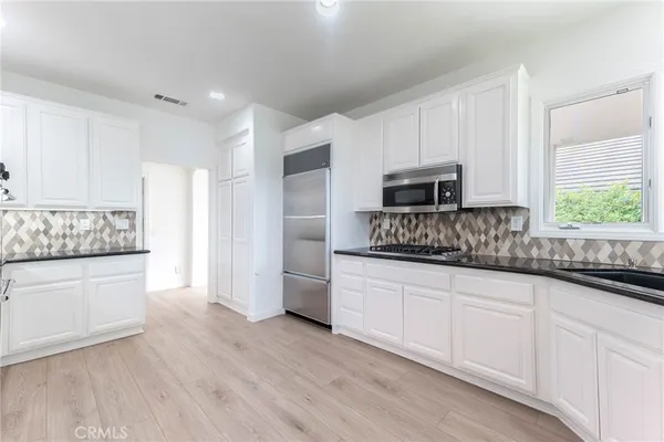 a kitchen with granite countertop white cabinets and stainless steel appliances