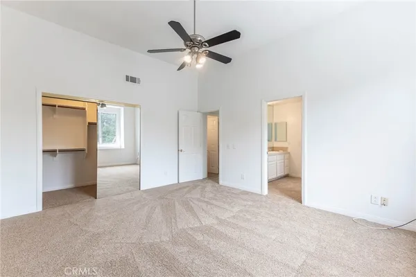 a view of a livingroom with a ceiling fan and kitchen space with wooden floor