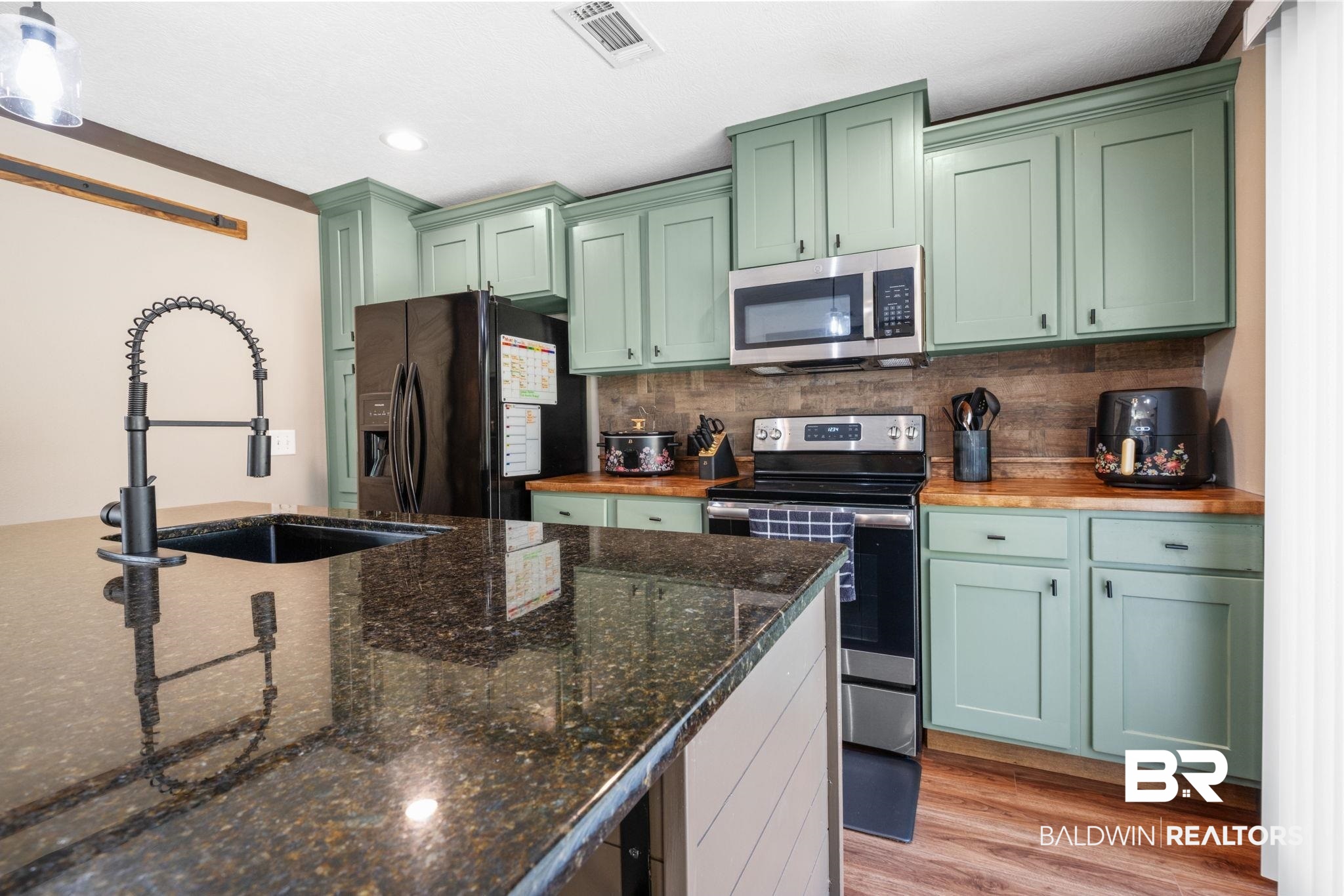 15080 Starlight Avenue Wilmer, AL 36587 - Photo 11 of 29 Kitchen with sink, light hardwood / wood-style flooring, green cabinets, stainless steel appliances, and dark stone counters
