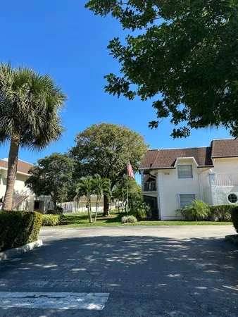 a view of a white house next to a yard with a tree