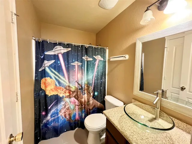 a bathroom with a granite countertop sink toilet and a mirror
