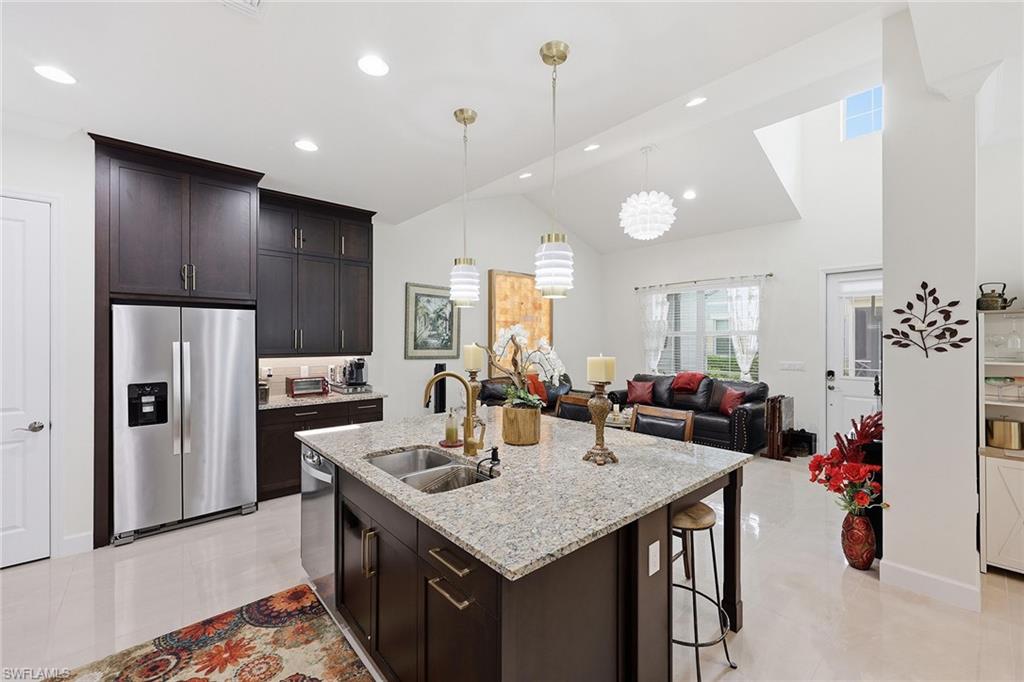 7204 Cayo Coco Lane Naples, FL 34113 - Photo 14 of 22 a kitchen with a refrigerator a stove and a dining table with wooden floor