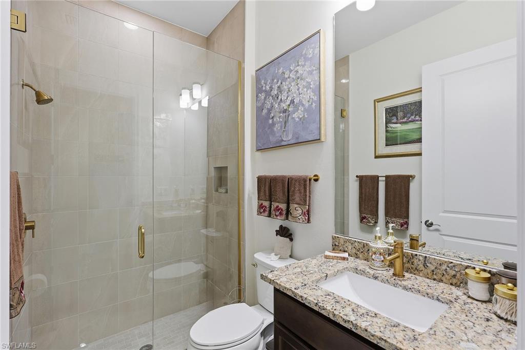 7204 Cayo Coco Lane Naples, FL 34113 - Photo 19 of 22 a bathroom with a granite countertop toilet sink and shower