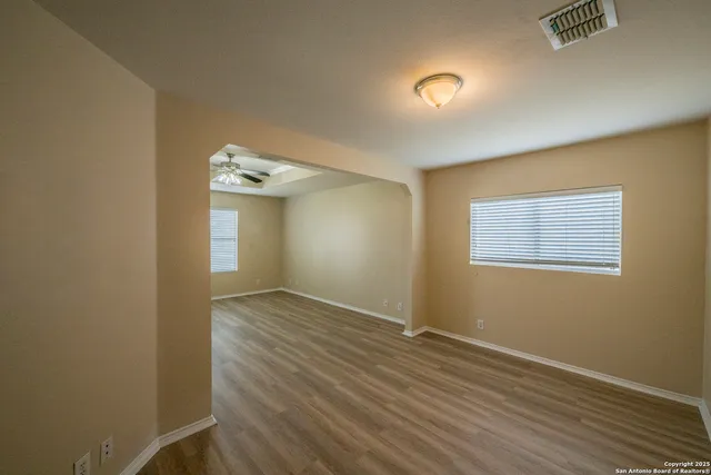 an empty room with wooden floor and windows