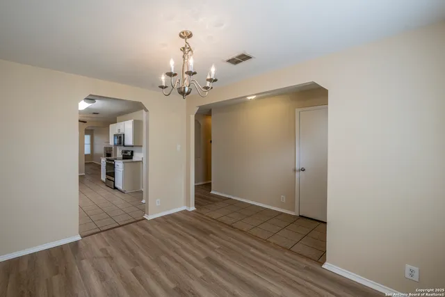 a view of a hallway with wooden floor and a bathroom