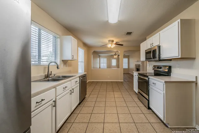 a large kitchen with stainless steel appliances granite countertop a stove top oven a sink dishwasher and white cabinets