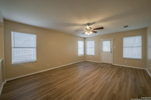 a view of an empty room with a window and wooden floor