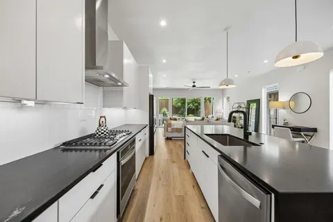 a kitchen with kitchen island granite countertop a sink a stove and a wooden floors