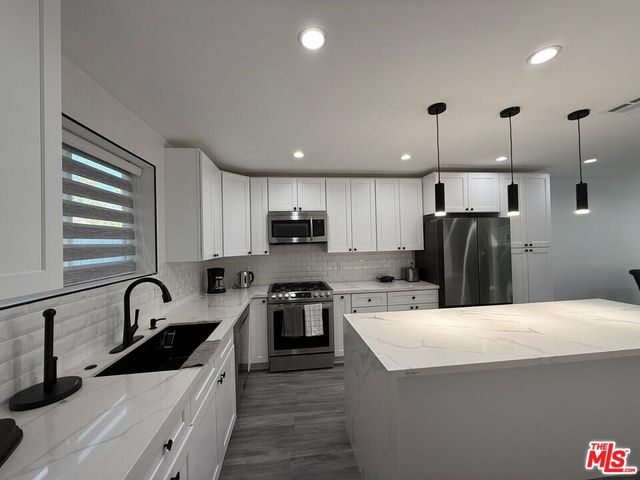 a kitchen with stainless steel appliances kitchen island a sink a stove and refrigerator