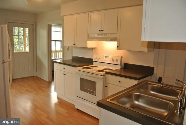 a kitchen with granite countertop a stove sink and cabinets