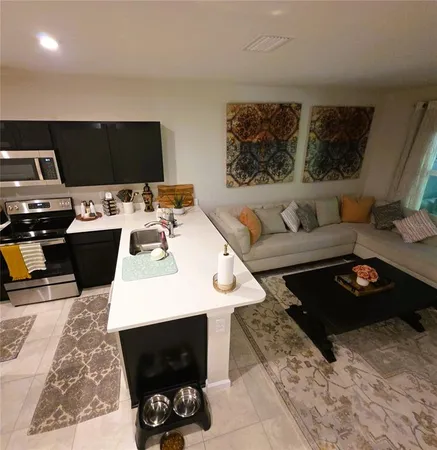 a living room with furniture flat screen tv and kitchen view