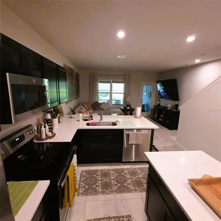 a large kitchen with stainless steel appliances a stove a refrigerator a sink a oven a dining table and chairs