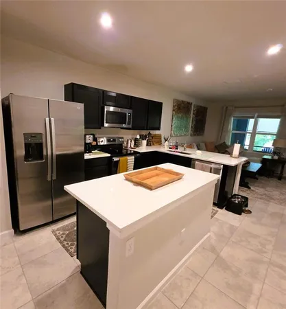 a kitchen with stainless steel appliances kitchen island sink refrigerator stove and microwave